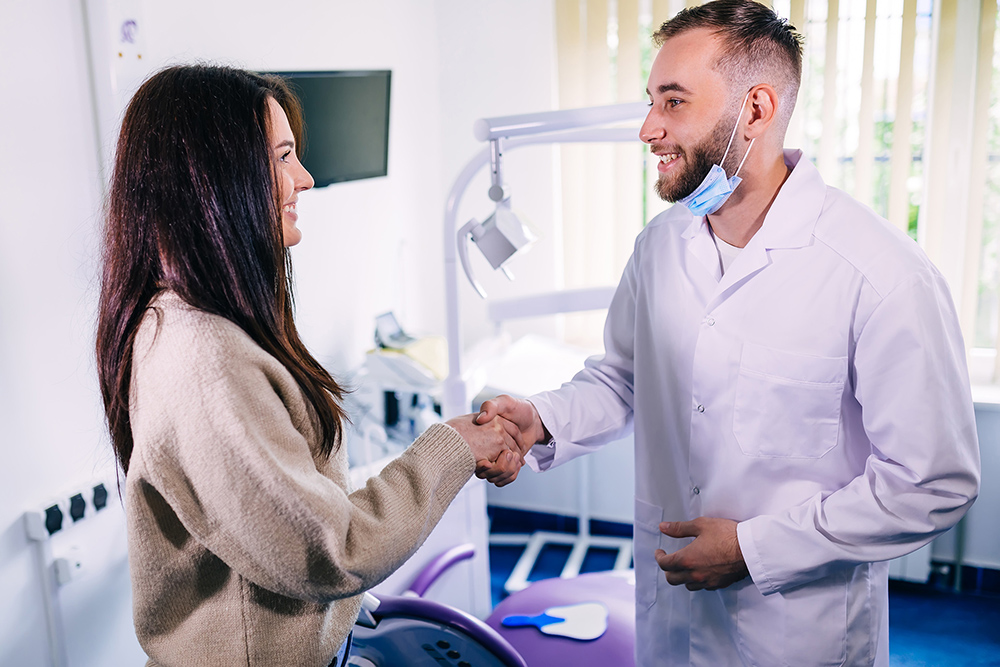 dentist in white medical uniforms shake hands greeting with a young patient. dentist office.